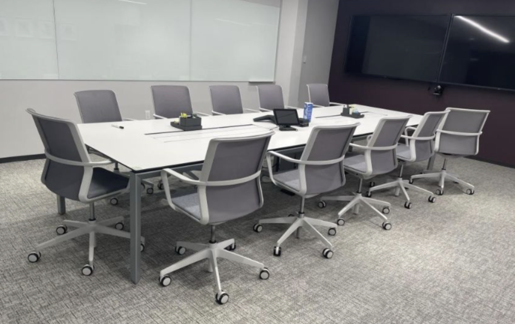 A conference room set consisting of a long table and 12 gray-white chairs is being auctioned for sale.